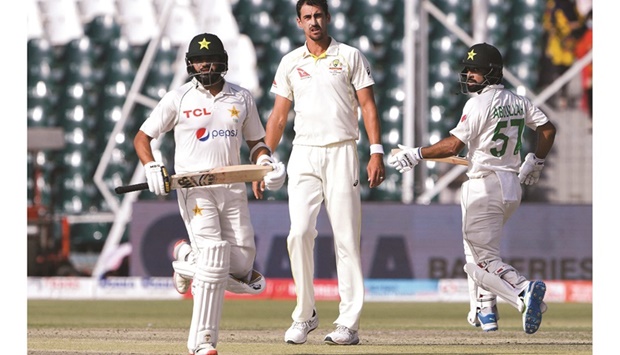 Australiau2019s Mitchell Starc (centre) watches as Pakistanu2019s Abdullah Shafique (right) and Azhar Ali run between the wickets during the second day of the third and final Test at the Gaddafi Cricket Stadium in Lahore yesterday. (AFP)