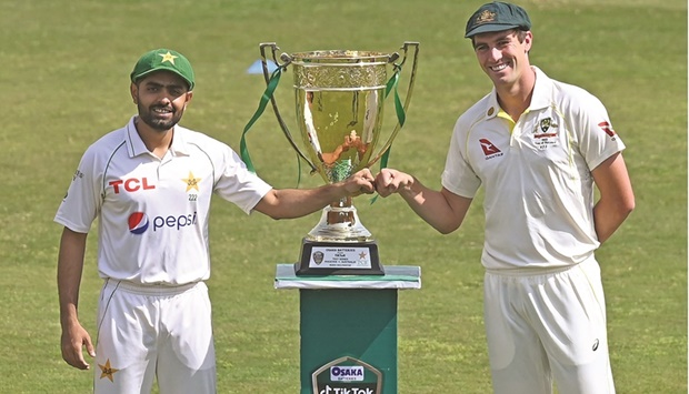 Pakistanu2019s captain Babar Azam (left) and his Australian counterpart Pat Cummins bump fists beside the Test series trophy prior to start the practice at the Pindi Cricket Stadium in Rawalpindi yesterday. (AFP)
