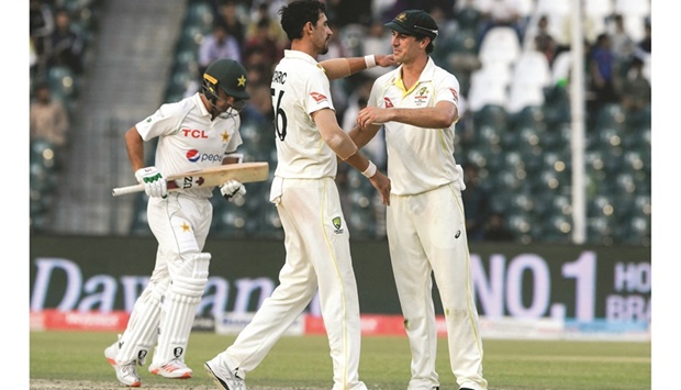 Australiau2019s Mitchell Starc (left) celebrates with his captain Pat Cummins after taking the wicket of Pakistanu2019s Naseem Shah during the third day of the third Test at the Gaddafi Cricket Stadium in Lahore yesterday. (AFP)