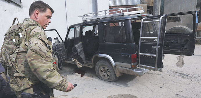 A US soldier from International Security Assistance Force (ISAF) is seen next to a vehicle used by an insurgent, who was killed by security forces in 