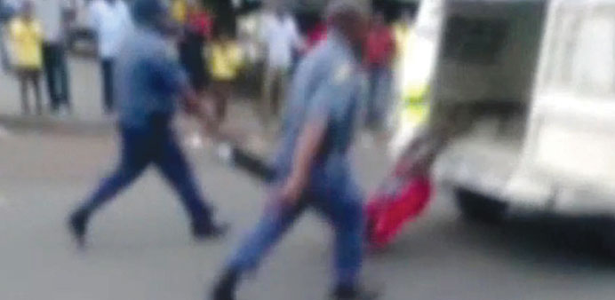 A picture grabbed on an amateur video and released by the South African Daily Sun newspaper shows South African policemen holding the legs of a Mozamb