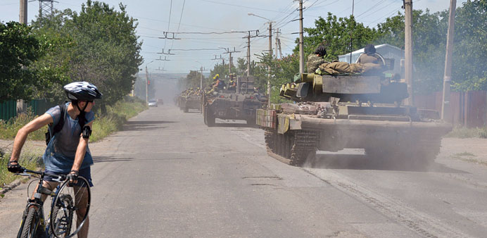 A cyclist watches as a convoy of Ukrainian armoured personnel carriers moves past him near the eastern Ukrainian city of Kramatorsk, in the Donetsk re