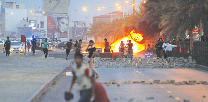    Protesters are seen on a street after setting fire to garbage containers during clashes with riot police in Budaya, west of Manama yesterday.