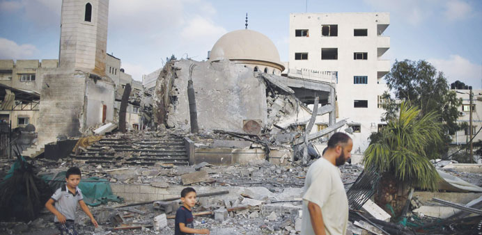 A man and two children walking past a mosque destroyed in the Israeli attack in Gaza. 
