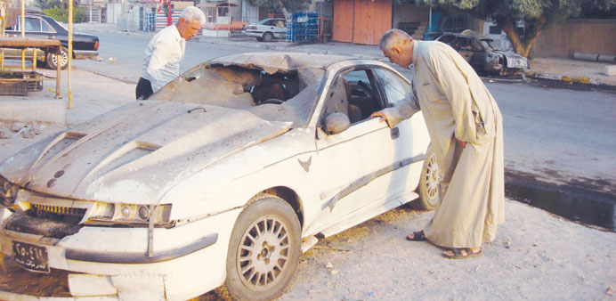 Residents inspecting a damaged vehicle after a car bomb attack in Baghdad.