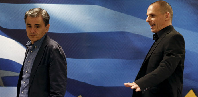 Outgoing Finance Minister Yanis Varoufakis (R) shows newly-appointed Finance Minister Euclid Tsakalotos his chair at the Finance Ministry 