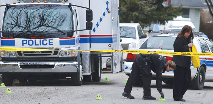 A police officer puts down evidence markers at a house where five people were stabbed in the early morning hours in Calgary, Alberta. Three people die