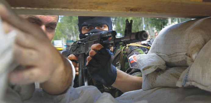 A heavily-armed pro-Russian rebel mans a newly-erected barricade on the road to Donetsk airport.