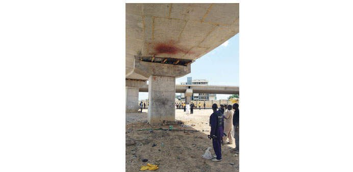 Members of the bomb squad stand under an uncompleted bridge where a suicide bomber tried to attack police officers after Eld al-Fitr prayers, in Kano.