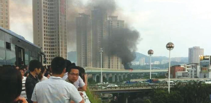 People look at smoke emitting from a bus, which is on fire, in Xiamen, Fujian province yesterday.