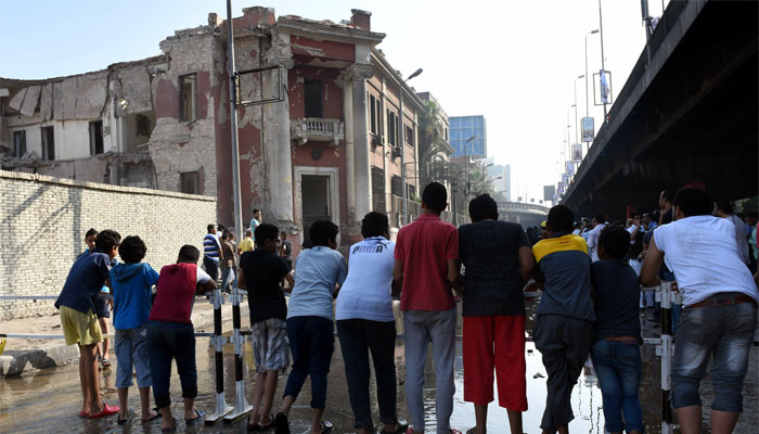 Egyptian citizens look at the  destroyed facade of the Italian consulate building in Cairo following a powerfu explosion.