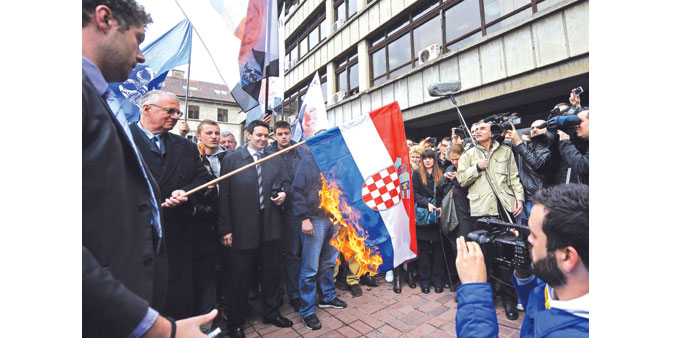 Surrounded by supporters, Serbian nationalist politician Vojislav Seselj burns a Croatian flag outside a tribunal in Belgrade.