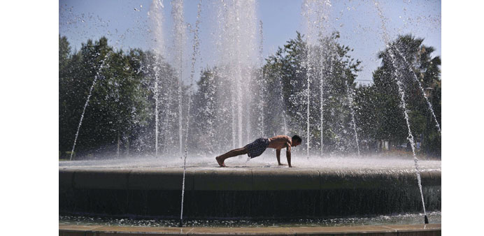 A man does push-ups as he cools off in a fountain in Seville.