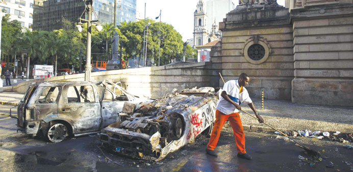  A municipal worker sweeps the streets by two cars burnt by demonstrators in downtown Rio de Janeiro, Brazil.