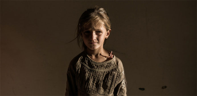 A Syrian refugee girl stands in a building in Syrian Kurdish city of Amuda