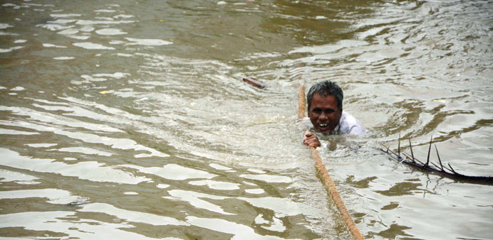 A man clings to a rope as he makes his way through floodwaters in Chennai.