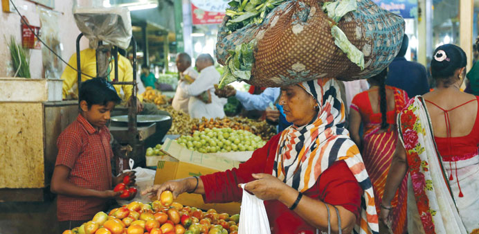A woman carrying cabbage leaves buys tomato at a market in Ahmedabad. Prices of vegetables like onions, tomatoes and potatoes have been rising, with s