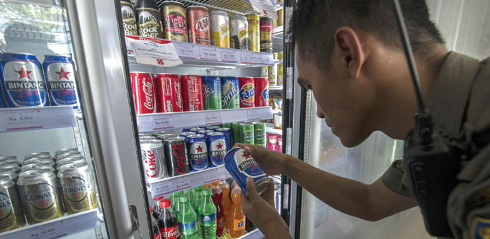 Civil security officer inspects the cold drinks section at a mini mart in Surabaya.