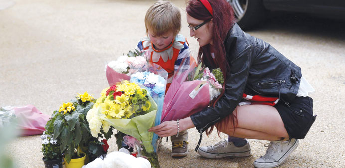 A mother and child place flowers outside a house where the bodies of three children were found, in New Malden, southwest London, yesterday.