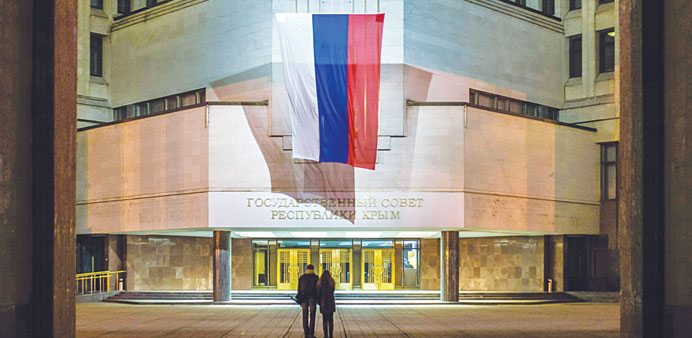People walk outside the building of the Crimean State Council, the former Crimean parliament, bearing a Russian flag in Simferopol.