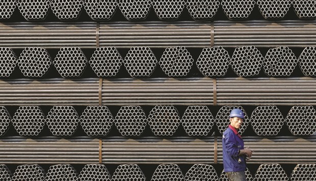 A worker walks past a pile of steel pipes at the yard of the Youfa steel pipe plant in Tangshan, Hebei province. The European Union opened three anti-dumping investigations into Chinese steel products and imposed new duties on imports after the European steel industry said thousands of jobs were at stake.