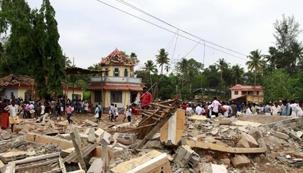People walk past debris on Sunday after a fire broke out at a temple in Kollam in the southern state of Kerala.