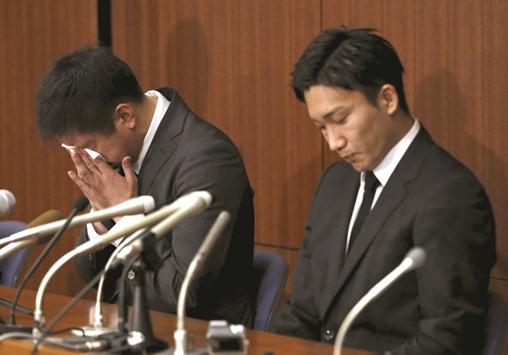 Japanese badminton player Kenichi Tago (L),  flanked by Kento Momota, wipes his tears during a news conference after reports on his gambling at an illegal casino in Tokyo, Japan. (Reuters)