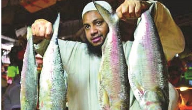 A vendor holds hilsa fish to show to buyers in a Dhaka market.