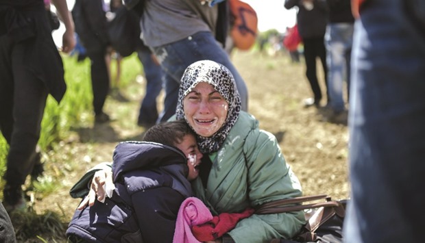 A woman and her child cry after being effected by tear gas used by Macedonian police to repel migrants and refugees who tried to storm the border. They have toothpaste smeared on their faces in an attempt to counter the effects of tear gas.