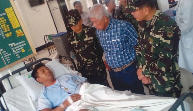 Philippines Defence Secretary Voltaire Gazmin (second right) and military chief General Hernando Iriberri (right) visit one of the 53 wounded soldiers at a military hospital in Zamboanga on the southern Philippine island of Mindanao yesterday, a day after soldiers clashed with the extremist Abu Sayyaf group.