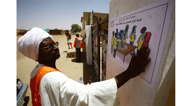 A member of electoral staff display informative posters at the entrance of a polling station in El-Fasher, in North Darfur yesterday, on the eve of the start of a referendum on whether to keep the conflict-torn western area as five states or to create one united region. Darfur region starts voting today on whether to unify its five states.