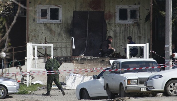 Investigators work near the entrance of a police station which was attacked