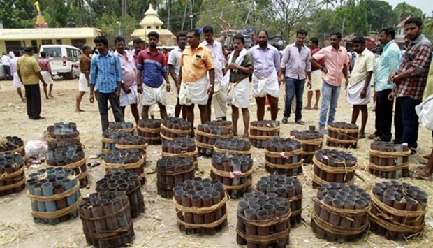 People stand next to empty fire cracker shells inside a temple compound where a fire broke out, in Kollam in Kerala.