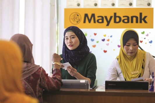 An employee serves a customer at the information counter inside a combined Malayan Banking (Maybank) and Maybank Islamic bank branch in Kuala Lumpur. The rally in Malaysian markets has so far withstood a probe into Prime Minister Najib Razaku2019s involvement in state investment company 1Malaysia Development, which has made progress in selling off assets to repay debt.