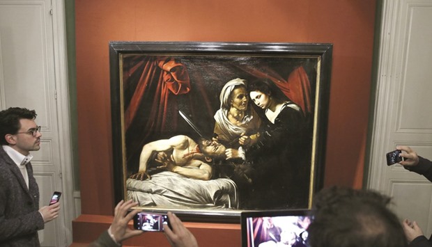 People take pictures of the painting entitled Judith cutting off the head of Holofernes, presented as being painted by Italian artist Caravaggio (1571-1610), while experts are still to determine its authenticity, yesterday in Paris.