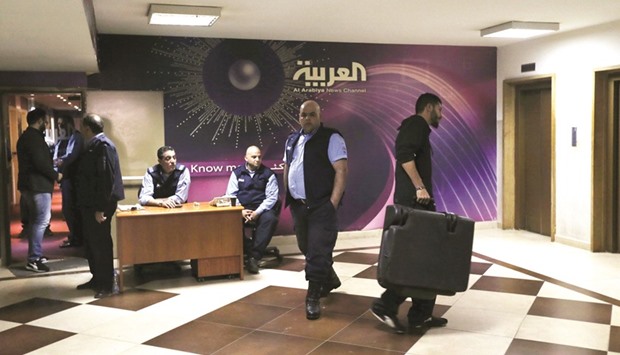 A man leaves while holding a suitcase as security personnel gather outside the offices of the television news channel Al Arabiya in Beirut yesterday.
