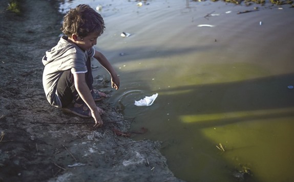 A boy plays with a paper boat at the makeshift camp by the Greek-Macedonian border, near the Greek village of Idomeni, where thousands of refugees and migrants are stranded by the Balkan border blockade.