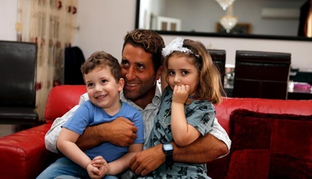 Noah (left) and Lahela al-Amin pose for a picture with their father Ali Zeid al-Amin in their family home in Beirut, Lebanon on April 8.
