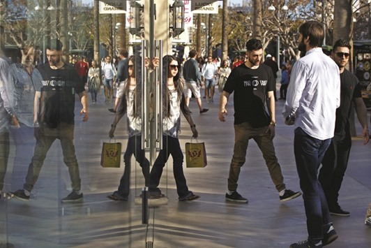 Shoppers are reflected in the window of a store at the Third Street Promenade in Santa Monica, California. The US retail sales unexpectedly fell in March as households cut back on purchases of automobiles and other items, further evidence that economic growth stumbled in the first quarter.