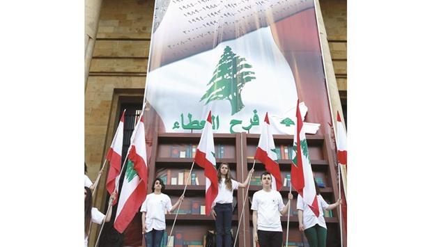Lebanese youths hold national flags during a rally organised by the Joy of Giving NGO to mark the 41st anniversary of the civil war in Lebanon yesterday in front of the National Museum.