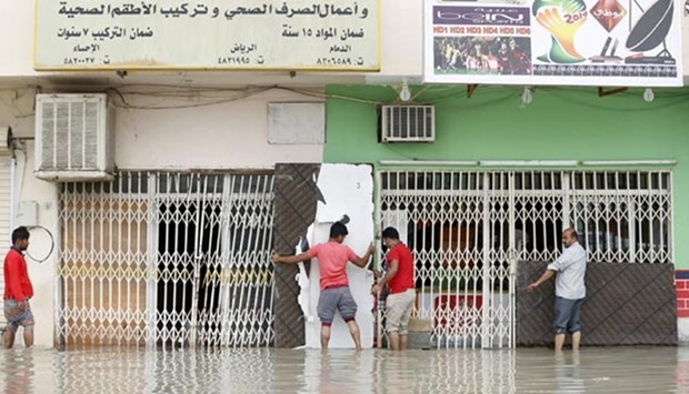 Men inspect flooded stores following heavy rain, in northern Riyadh.
