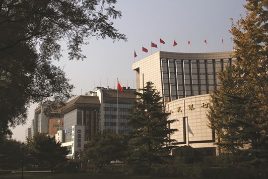 The Peopleu2019s Bank of China headquarters (right) is seen in Beijing. The PBoC has lowered benchmark interest rates six times since 2014, driving a record rally in the bond market and underpinning a jump in debt to 247% of gross domestic product.