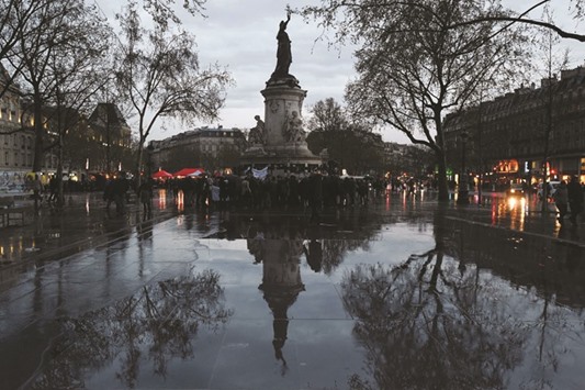 A picture taken on Thursday evening in Paris shows the statue on the Place de la Republique reflected on water as people take part in the u2018Nuit Deboutu2019 (Up All Night) movement, to protest against the governmentu2019s labour reform.