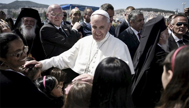 Pope Francis greets children as he leaves the port of Mytilene