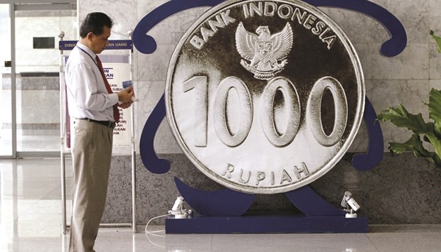 An employee of Bank Indonesia stands next to a giant one thousand rupiah coin on display inside the banku2019s headquarters in Jakarta. The central bank said it will use the seven-day reverse repo rate as its benchmark policy instrument to help spur lending and support growth in Southeast Asiau2019s biggest economy.