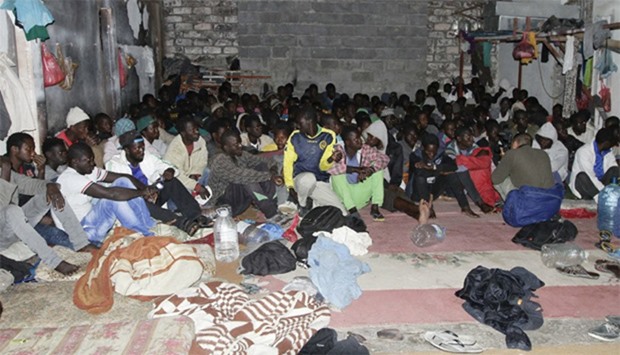 Illegal migrants sit huddled at a hideout after Libyan security forces conducted a raid in Tripoli, 