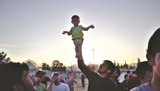 A man holds a child aloft at the makeshift migrant and refugee camp near the Greek village of Idomeni on the border with Macedonia.