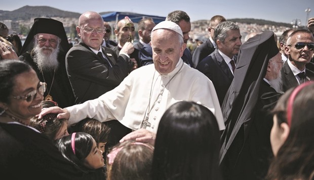 This picture taken on Saturday shows Pope Francis greeting people gathered to welcome him at the port of Mytilene on the Greek island of Lesbos. He later left for the Vatican with 12 Syrian refugees.
