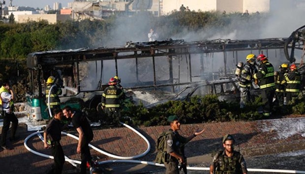 Israeli security forces stand guard as firemen extinguish a burning bus following an attack in Jerusalem on Monday.