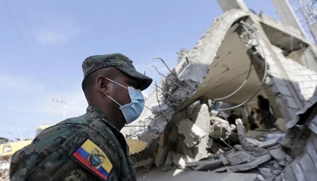 A soldier walks past a collapsed building after an earthquake struck off the Pacific coast, in Pedernales, Ecuador on Tuesday.